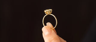 Photo shows a model holding up the Melanie Casey Wreathed Ring with a champagne diamond, showing off it's side profile.