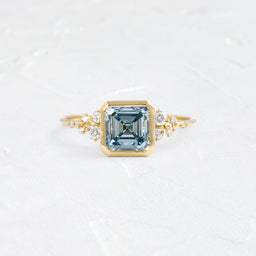 Image showcases a Bezel Snowdrift Ring, 2.01ct. Lab-Grown Asscher Cut Blue Diamond on a textured white background.