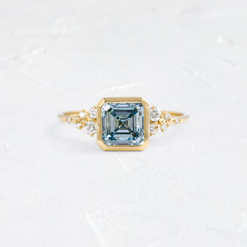 Image showcases a Bezel Snowdrift Ring, 2.01ct. Lab-Grown Asscher Cut Blue Diamond on a textured white background.