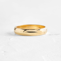 Photo shows a Melanie Casey Men's Half Round Band sitting on a textured white background.