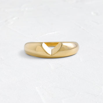 The Melanie Casey Allusion Band in 14k Yellow Gold shown from a front view sitting on a textured white background.