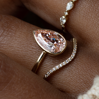 This photo showcase a model wearing the Vester Engagement Ring in Pear cut with a 2ct pink center stone and a 1.5mm width band.