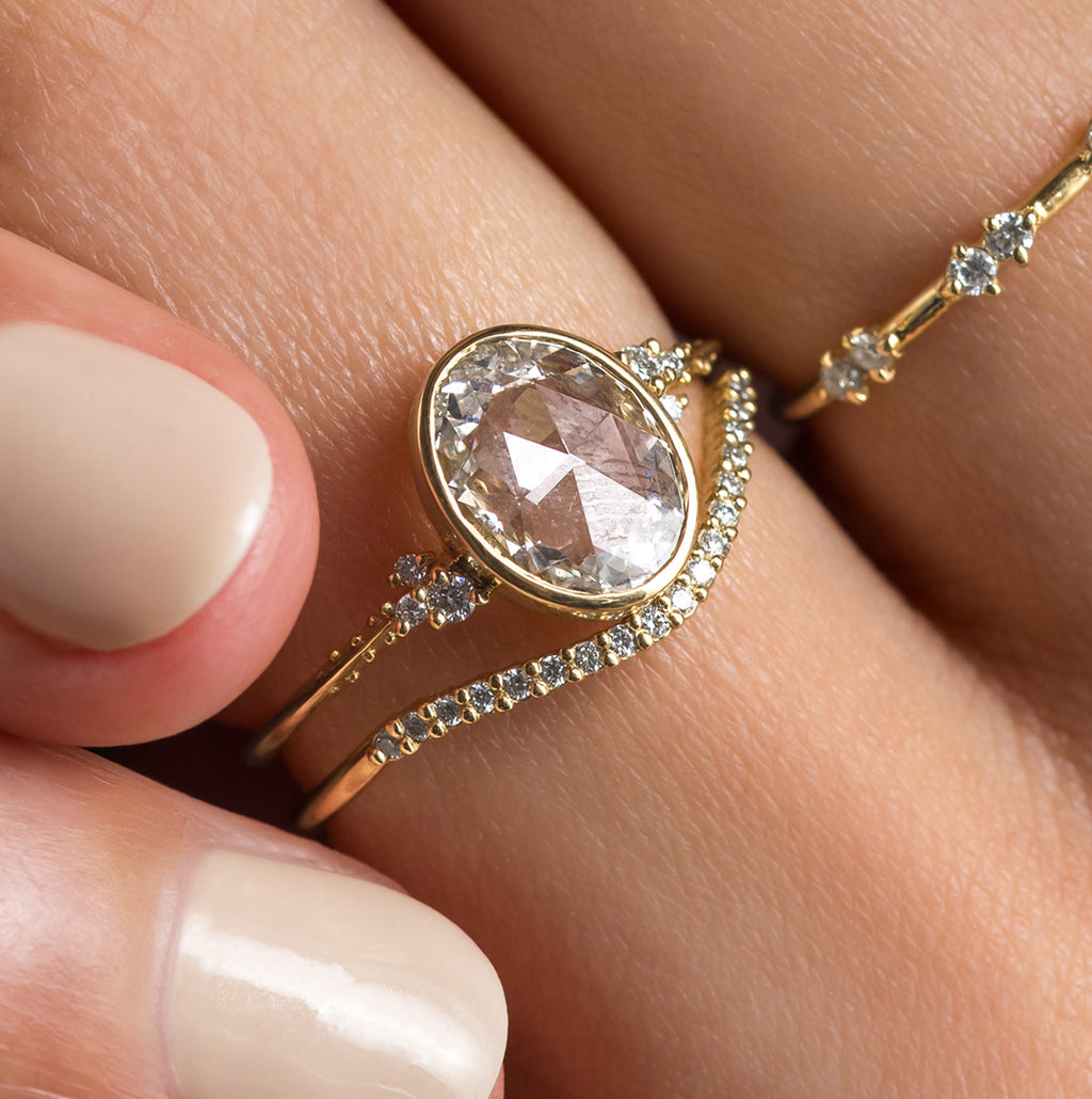 Photo features someone wearing the Bezel Engagement Pensive Ring in Oval and Rose Cut on her hand.
