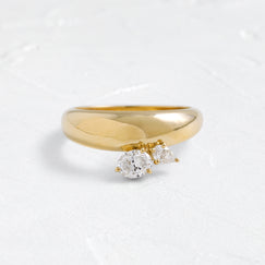 The Melanie Casey Epilogue Band in 14k Yellow Gold shown from a front view sitting on a textured white background.