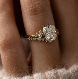 Model wearing the Melanie Casey Snowdrift Bezel Set Ring with a Cushion Cut center stone, shown from a three quarter side profile view.