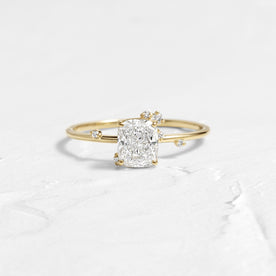 To A Flame Cushion Cut Engagement Ring in Yellow Gold by Melanie Casey shown on a textured white background