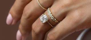 Photo showcases a model wearing the Melanie Casey Touchpoints Ring with an elongated Cushion Cut center stone.