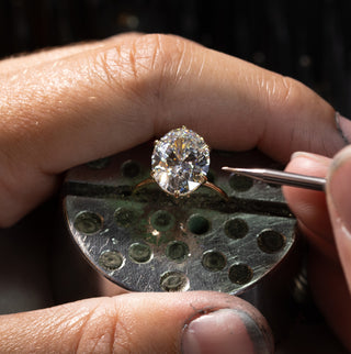 Oval Melanie Casey Diamond Engagement Ring being worked on by a jeweler at the bench.