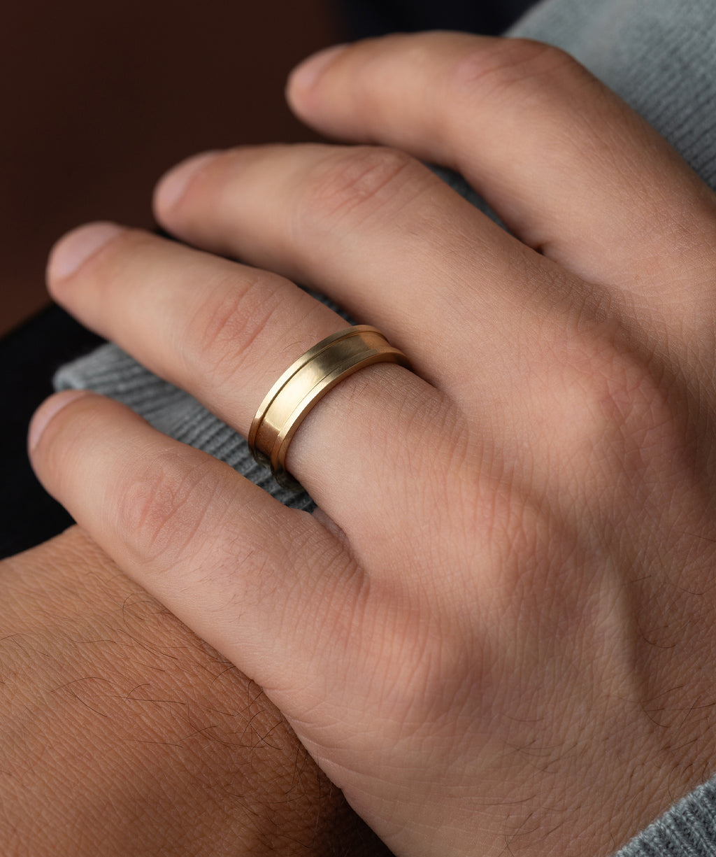 Photo showcases a model wearing the Melanie Casey Men's Square Band on one hand, with it resting on his other wrist.