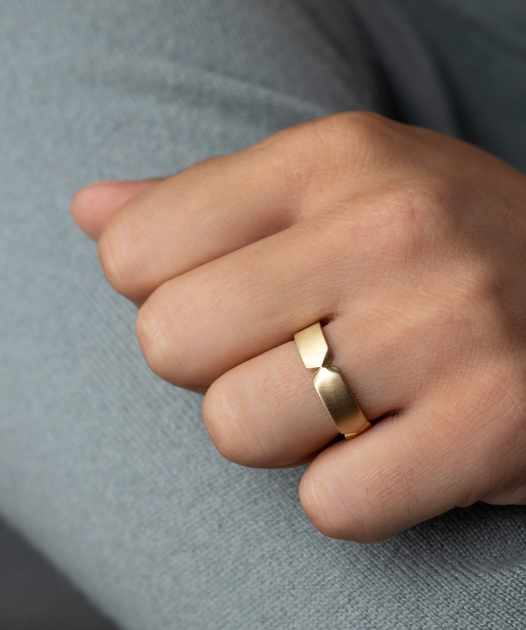Photo showcases the Melanie Casey men's Checkpoint Band on a model's hand, which is closed and sits against the side of his arm.