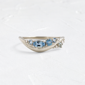 Photo features the front view of the Rising Tide band in white gold, shown on a textured white background.