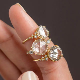 Photo showcases several Melanie Casey rose cut diamond engagement rings stacked on one finger.
