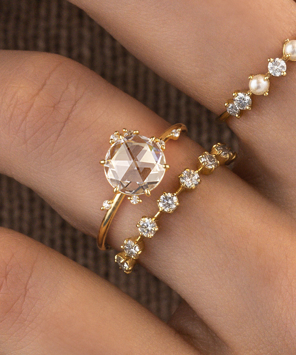 Photo showcases a model wearing the To A Flame Rose Cut Ring paired on top of the Distance Band on her hand. The Pearl Inlet Band is styled alongside the set.