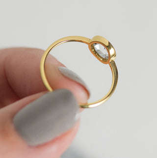Photo features the Melanie Casey Edifice Bezel Ring being held up by a model between two fingers.
