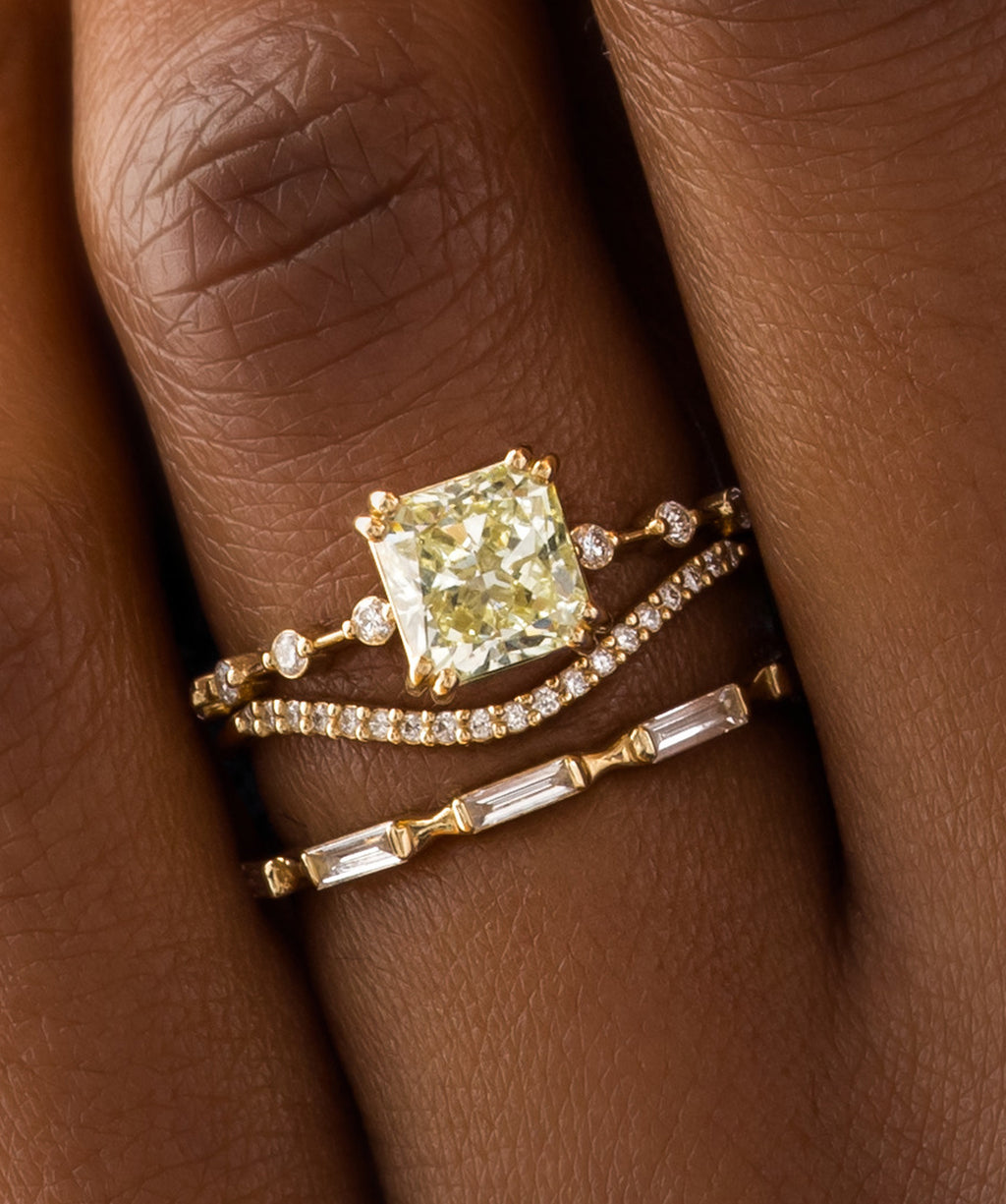 Photo features a model wearing the Melanie Casey  Distance Ring with a yellow diamond center stone.
