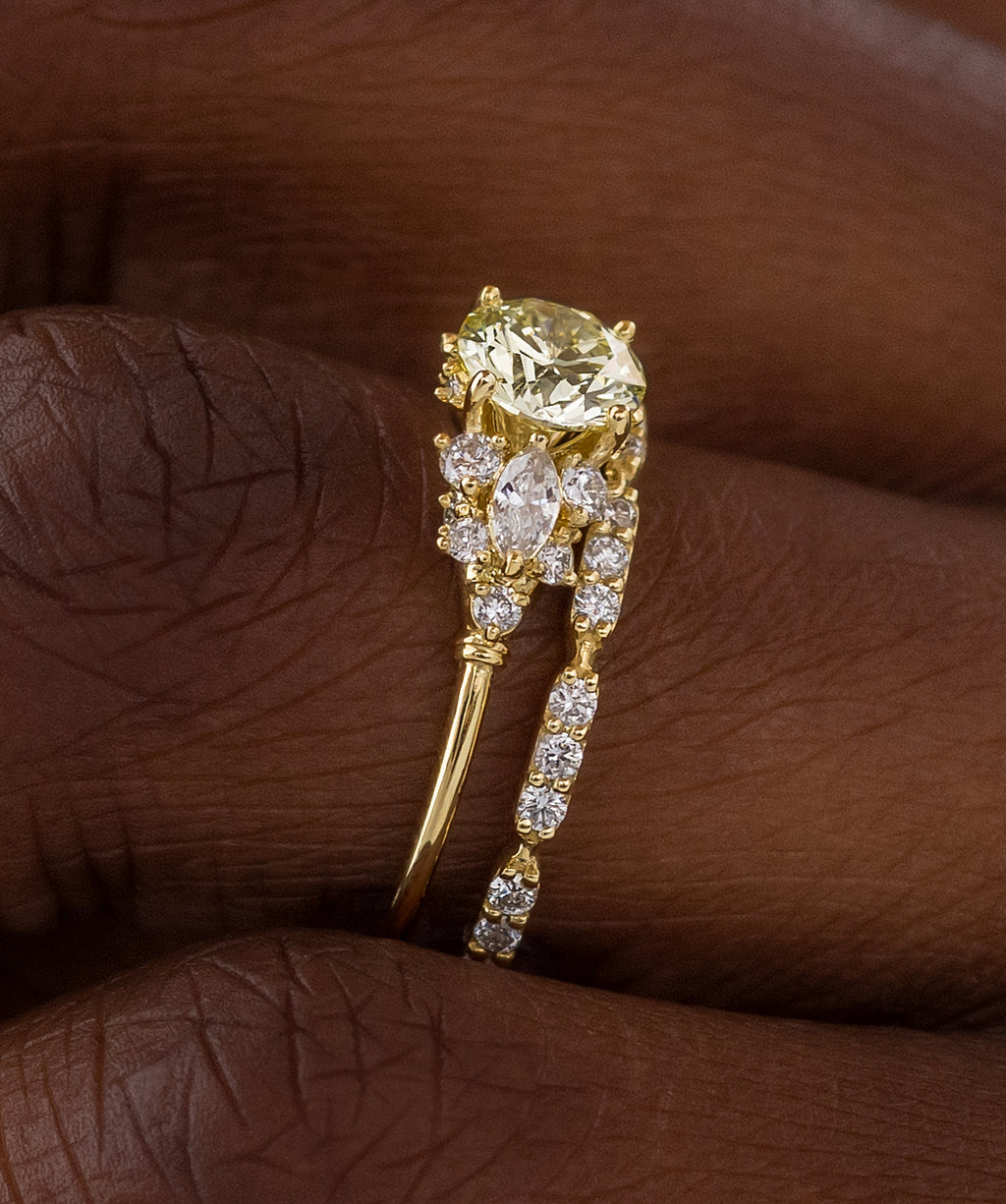 Photo features a model wearing the Melanie Casey Nebula Ring with a round cut yellow diamond center stone, showing off the side profile of the ring.