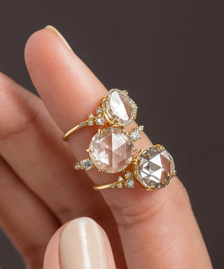 Photo showcases several Melanie Casey rose cut diamond engagement rings stacked on one finger.