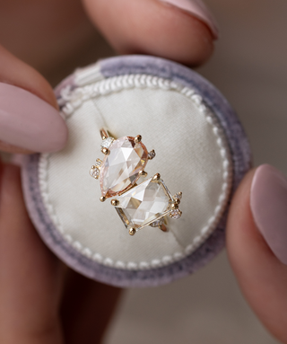 Photo features the one of a kind Melanie Casey Rose Cut Clarity Ring being held up by a model in a round ring box.