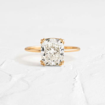 Threaded Cushion Cut Ring Engagement Ring in Yellow Gold by Melanie Casey shown on a textured white background
