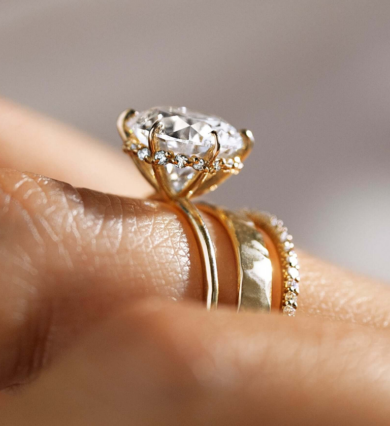 This photo features a model wearing the Touchpoints Ring in Round Cut on her ring finger, shown in close detail from the lower 3/4 profile view of the ring, highlighting its hidden diamonds.