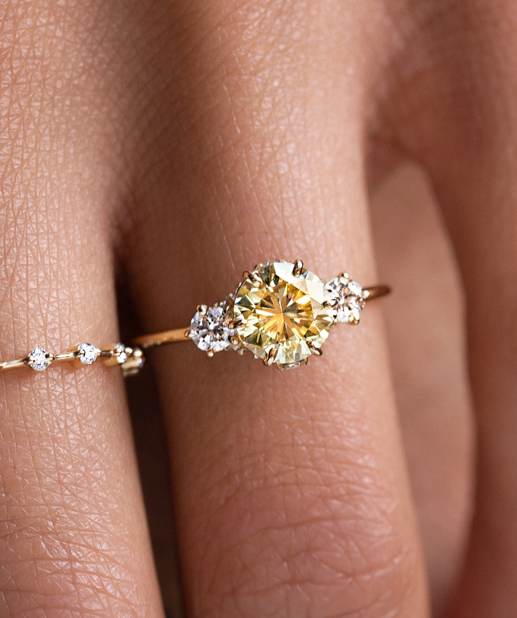 Photo features a model wearing the Melanie Casey  Daybreak Ring with a yellow diamond center stone.