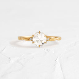 Twine Ring, Rose Cut Engagement Ring in Yellow Gold by Melanie Casey shown on a textured white background